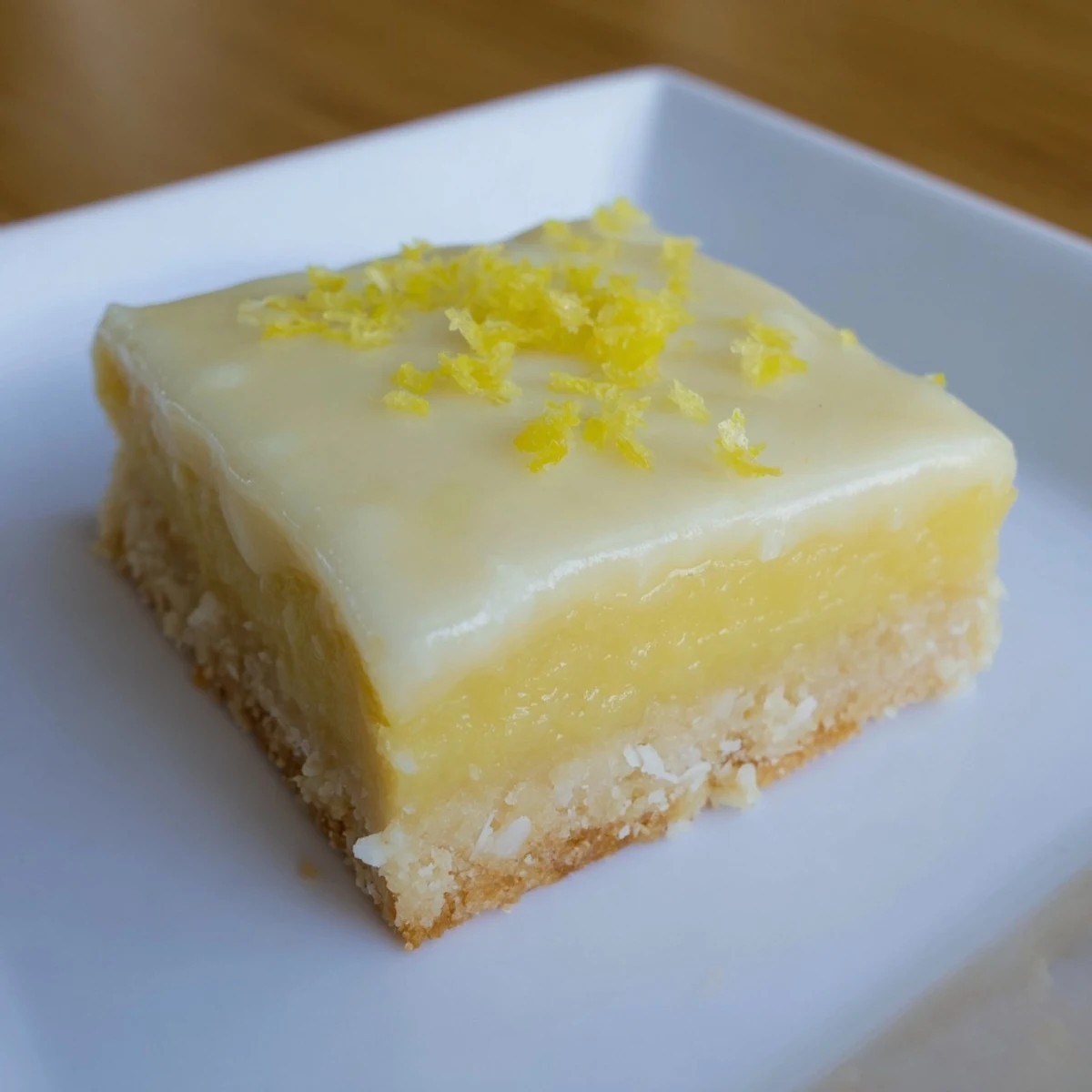 A close-up of freshly cut Lemon Slice, revealing a creamy lemon layer over a biscuit crust.