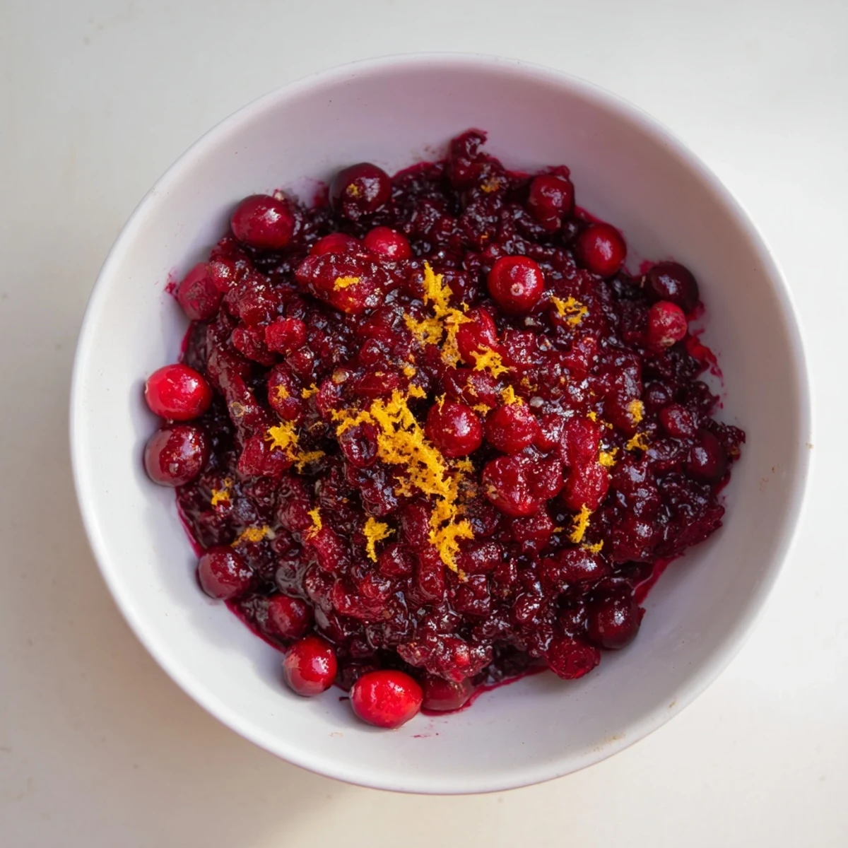 Bright red Cranberry Sauce with Orange Zest, shimmering, ready to spoon over a holiday turkey.