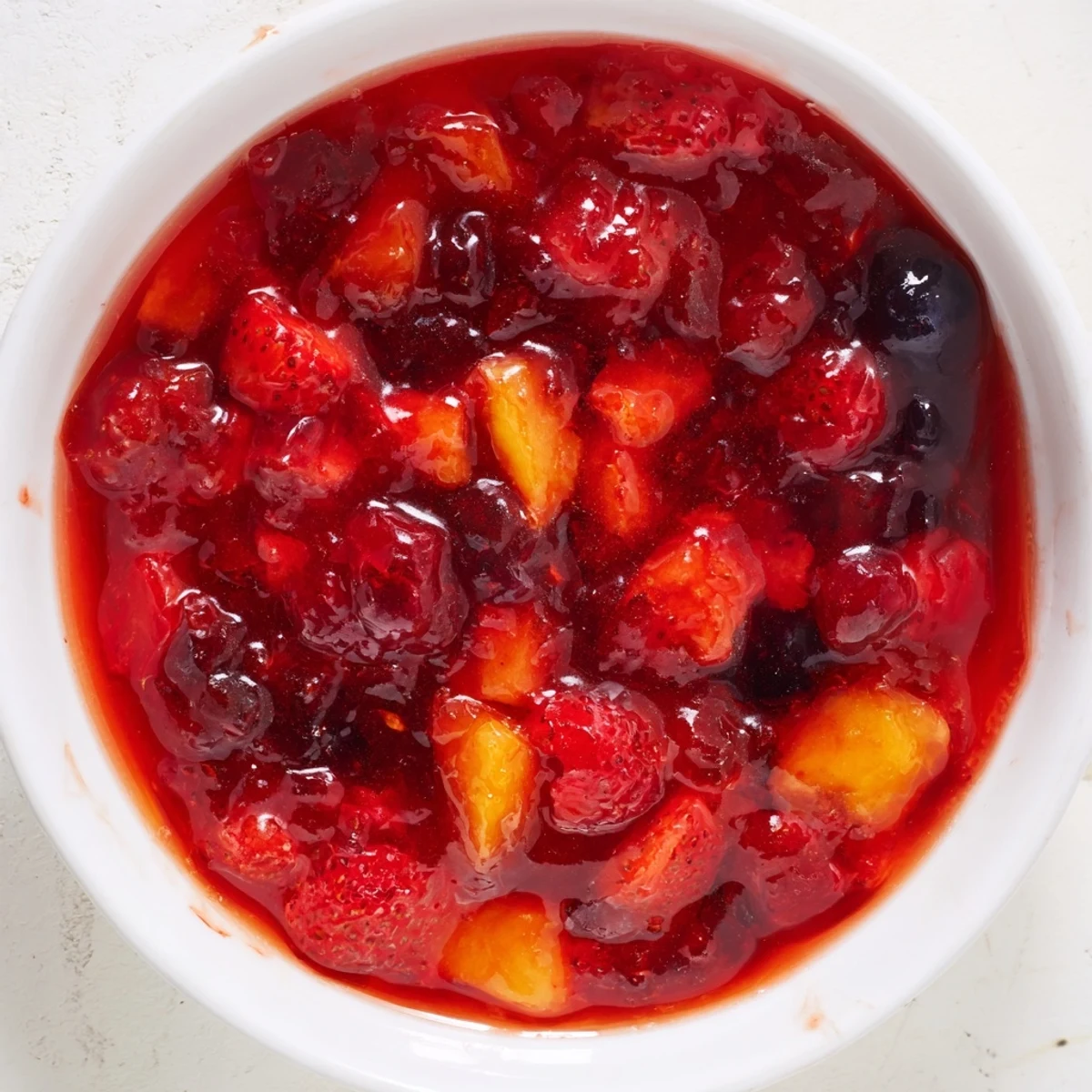 A jar of homemade fruit jam, a vibrant mix perfect for toast or desserts.