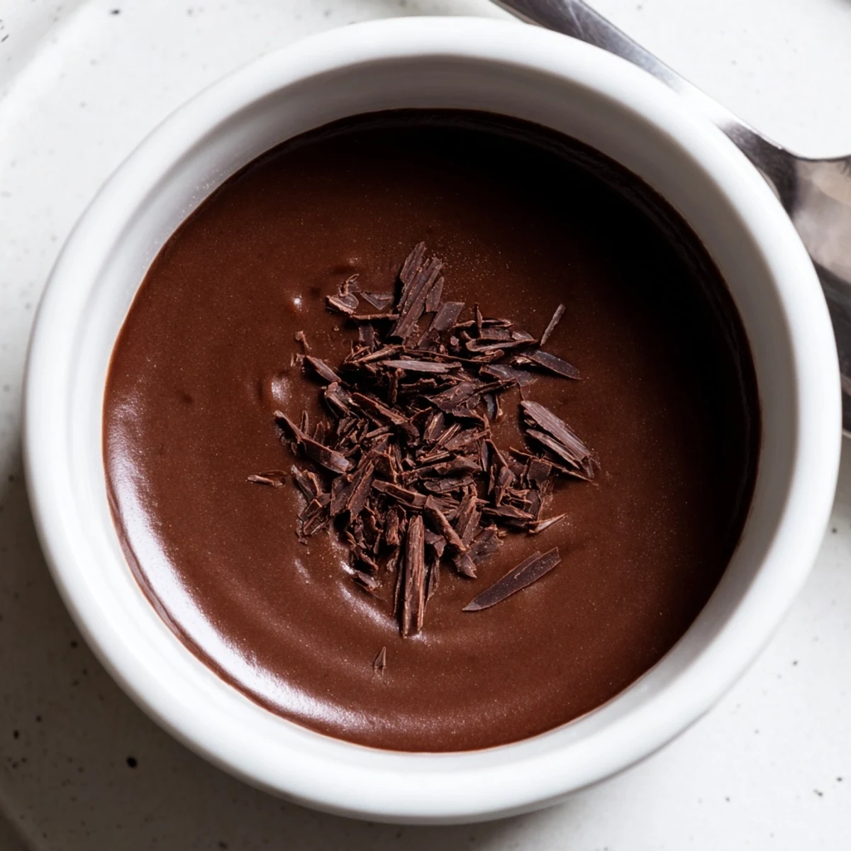 A delightful portion of creamy, glistening dark chocolate pudding, waiting temptingly for a sweet treat.
