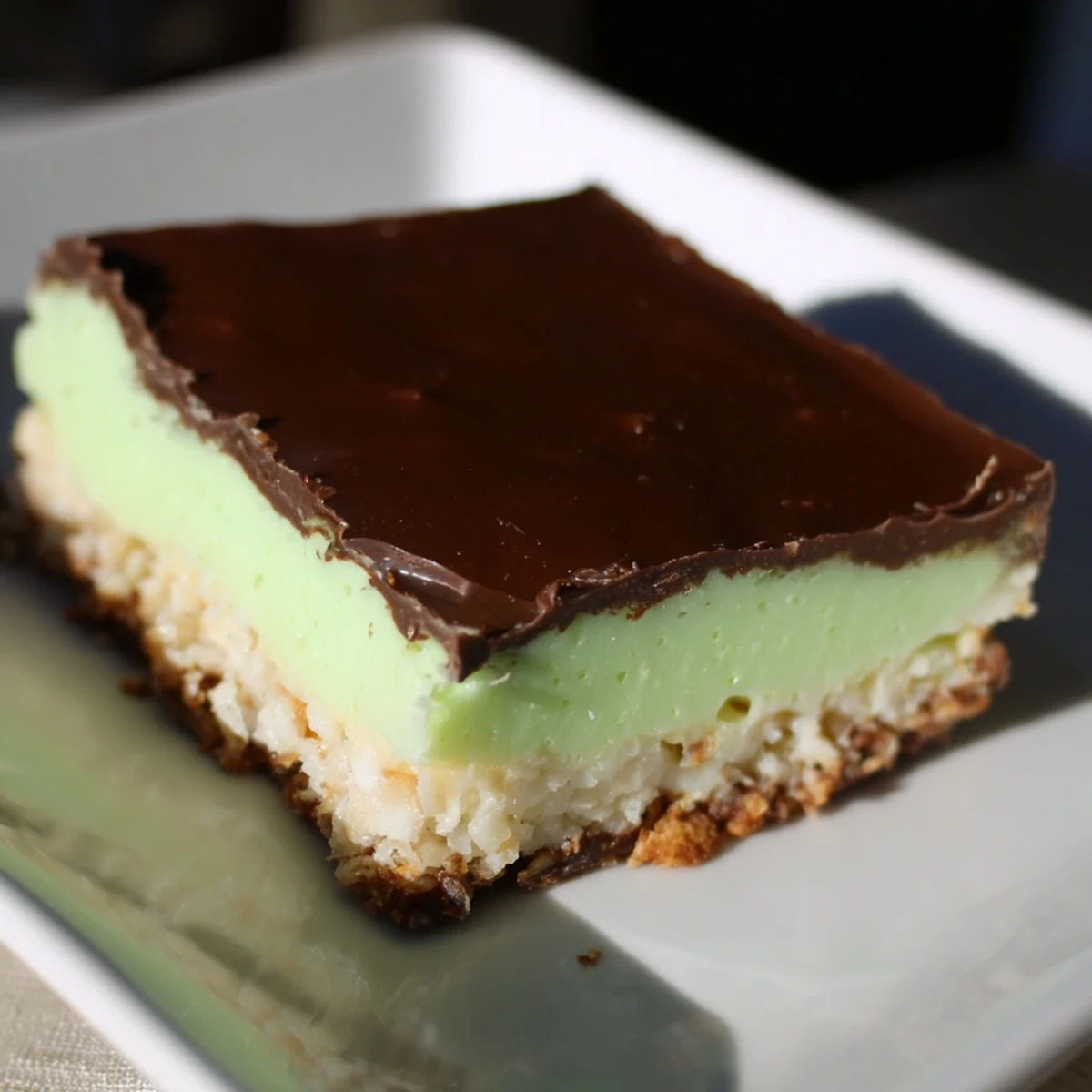 A close-up of a festive Peppermint Slice, showing the creamy mint filling and chocolate top.