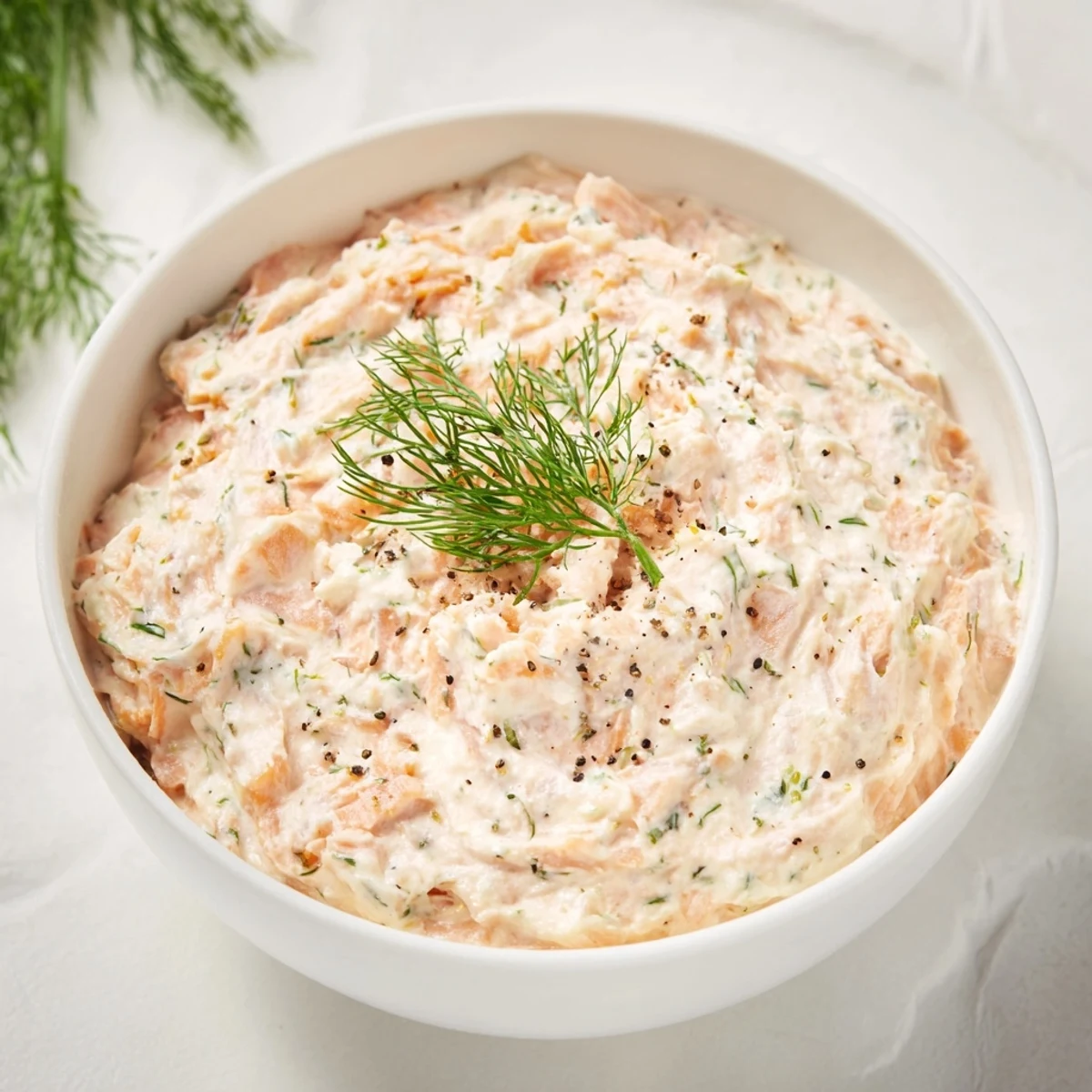 Creamy smoked salmon pâté spread on crackers, garnished with fresh dill, ready to serve.