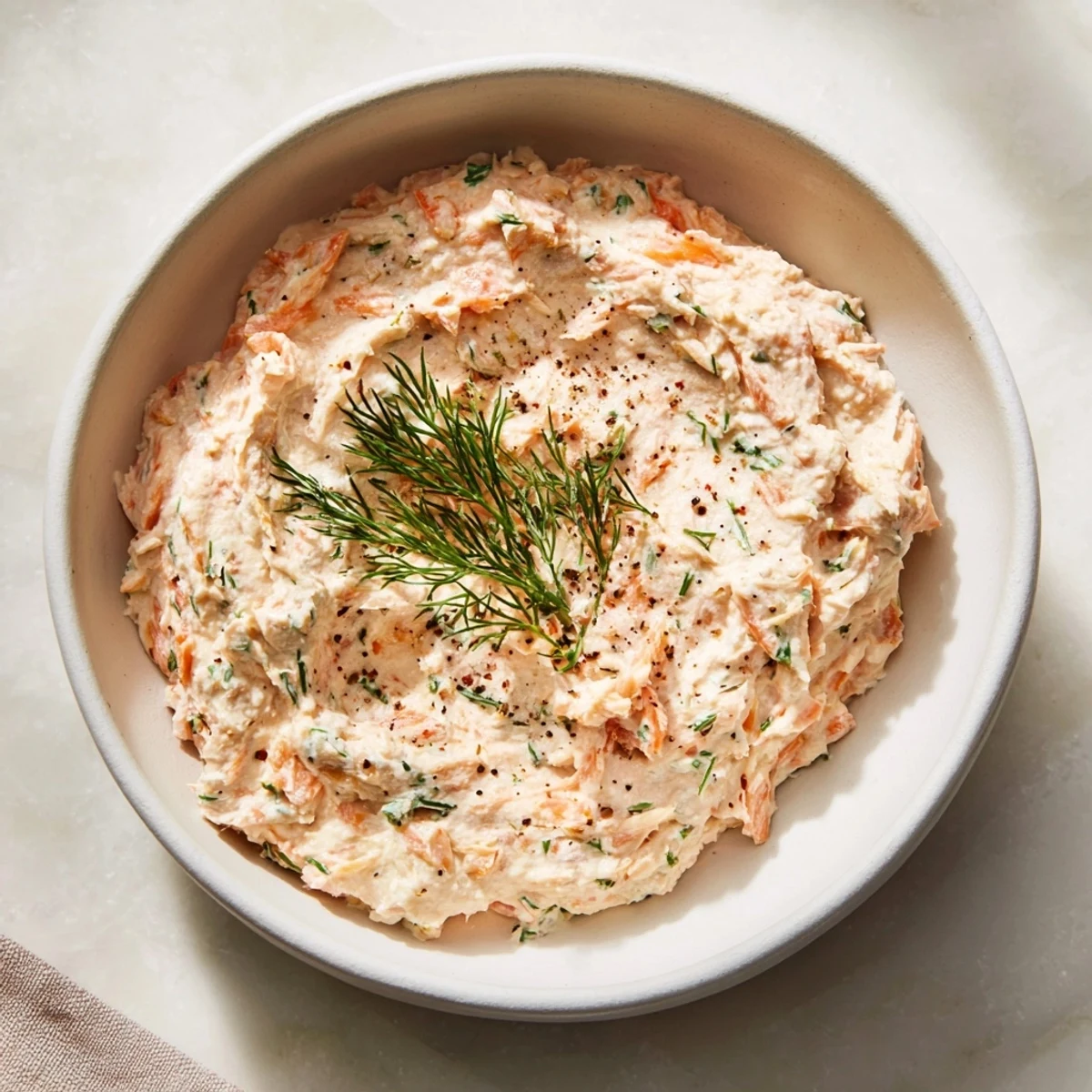 Close-up of a vibrant smoked salmon pâté, showing its creamy texture and fresh herbs.