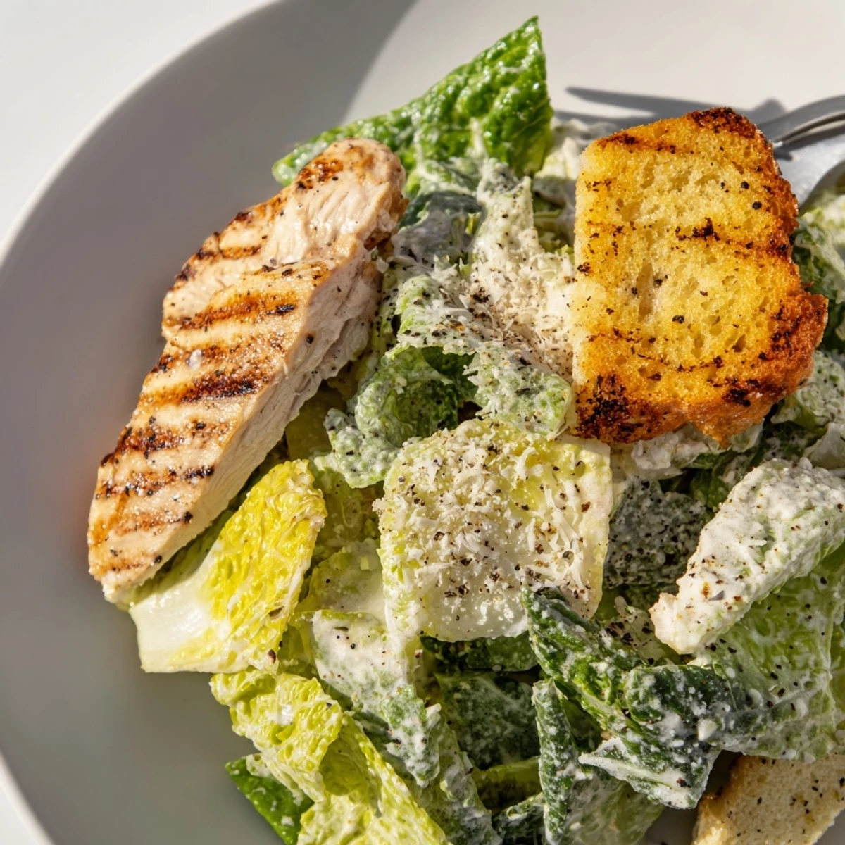 A fresh, vibrant bowl of Chicken Caesar Salad with Homemade Garlic Croutons, featuring grilled chicken slices on crisp romaine.