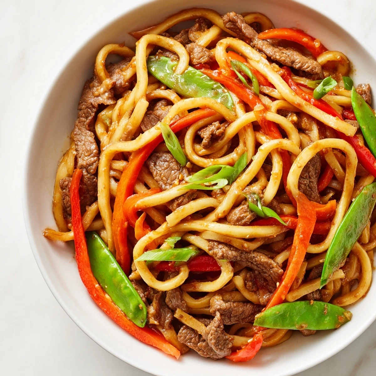 Spicy Beef Stir Fry with Udon Noodles served hot with crisp vegetables and a glossy, savory sauce.