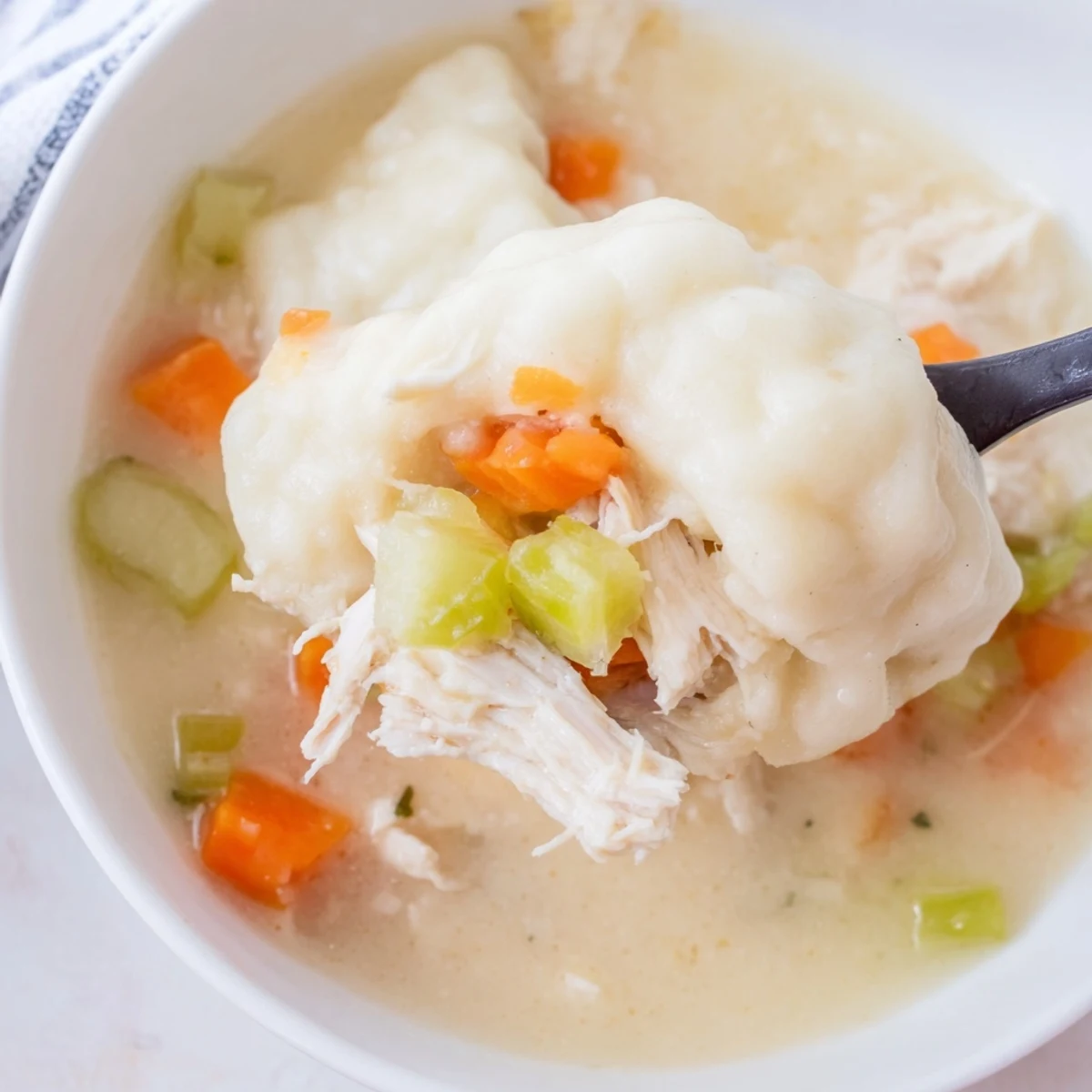 Slow Cooker Chicken and Dumplings stew bubbling in a slow cooker, featuring tender shredded chicken and fluffy dumplings in a creamy broth with peas and carrots.