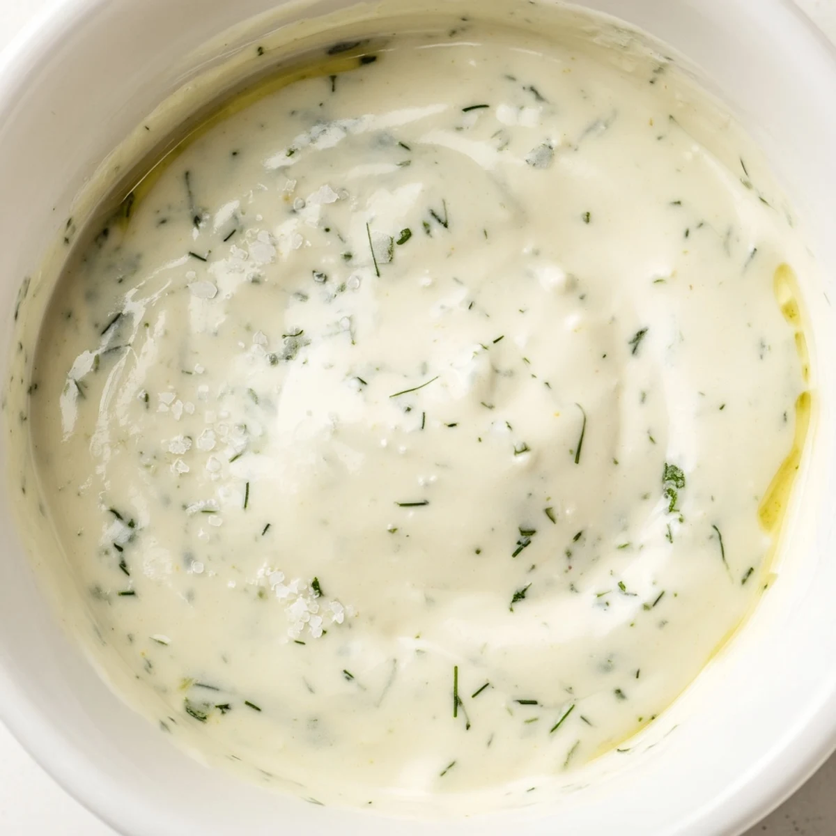 Cremiges Kräutersalatdressing mit glatter Textur, frischen Kräutern und einem Hauch Zitrone auf einem Glasbehälter.