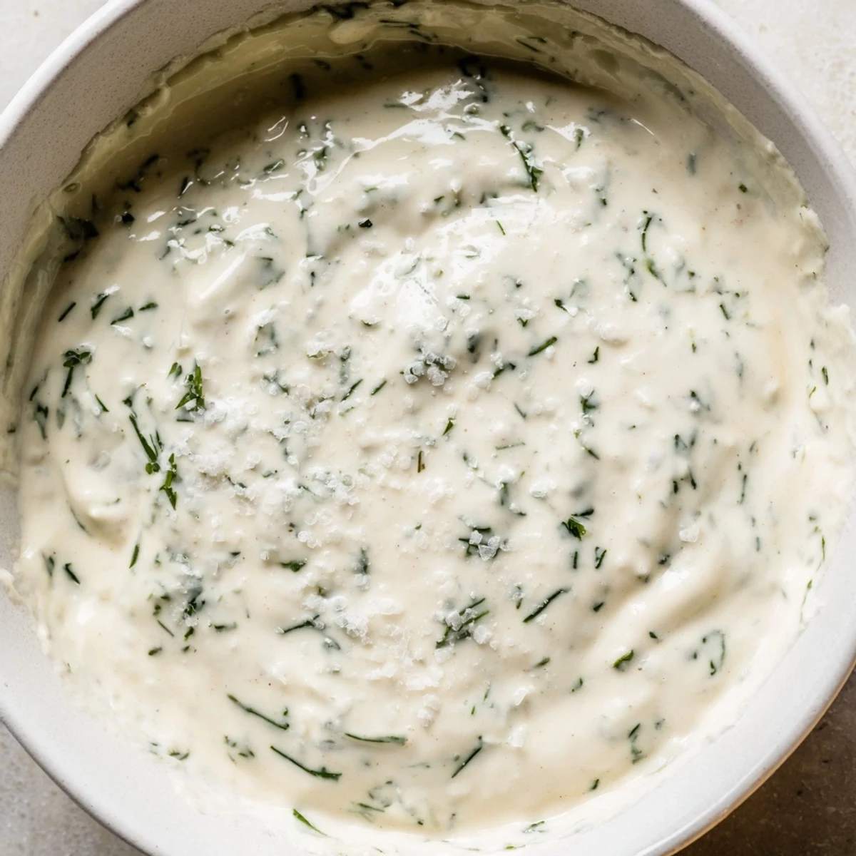 Cremiges Kräutersalatdressing in einer Glasvase, umringt von frischen Kräutern, perfekt für den nächsten gemischten Salat.