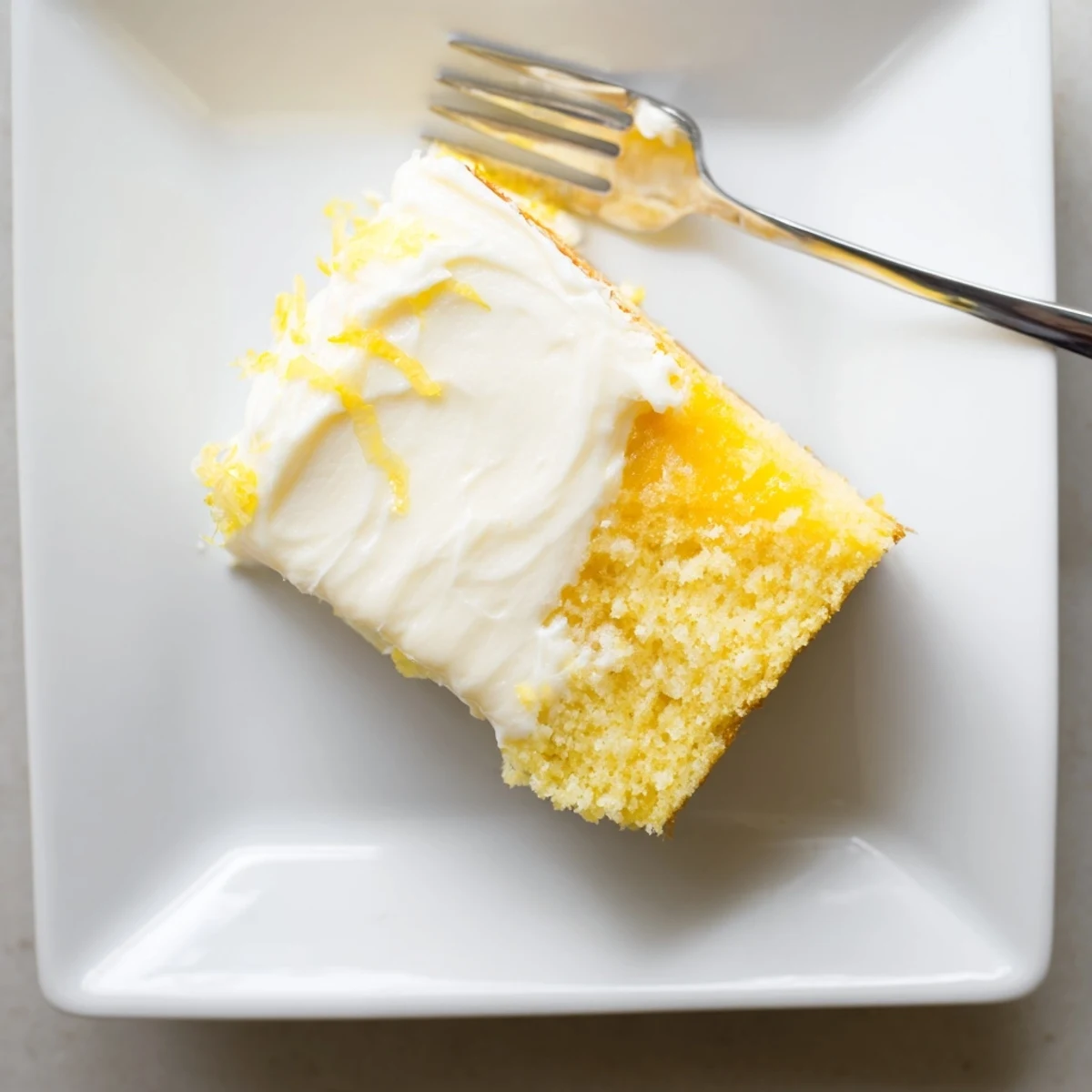 Eine feuchte, zitronig leckere Lemon Cake Slice mit cremiger Zitronen-Creme-Cheese-Frosting, perfekt für den Teetisch.
