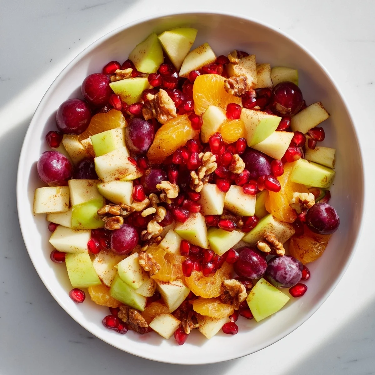 Healthy Winter Snack Fruit Mix with colorful fruits, a sprinkle of cinnamon, and optional pecans on a bright kitchen counter.