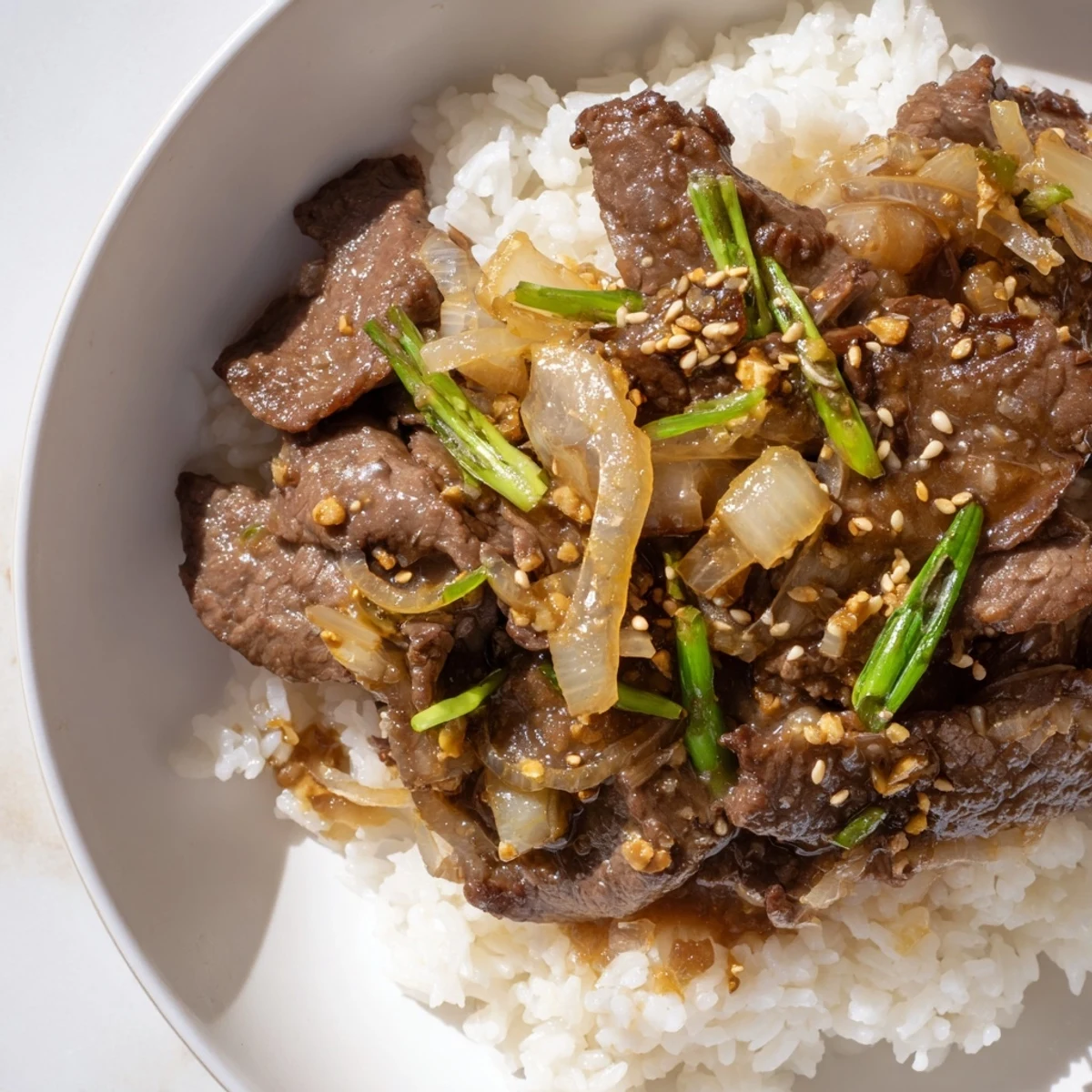 Saftige Rinderstreifen in würziger Sauce über dampfendem Reis, serviert in einer gemütlichen Schüssel.