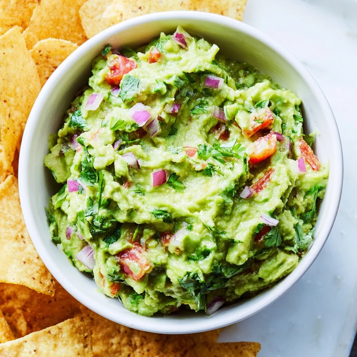 Frisch pürierte Big Game Guacamole mit knusprigen, selbstgemachten Tortilla-Chips auf einer Partyplatte.