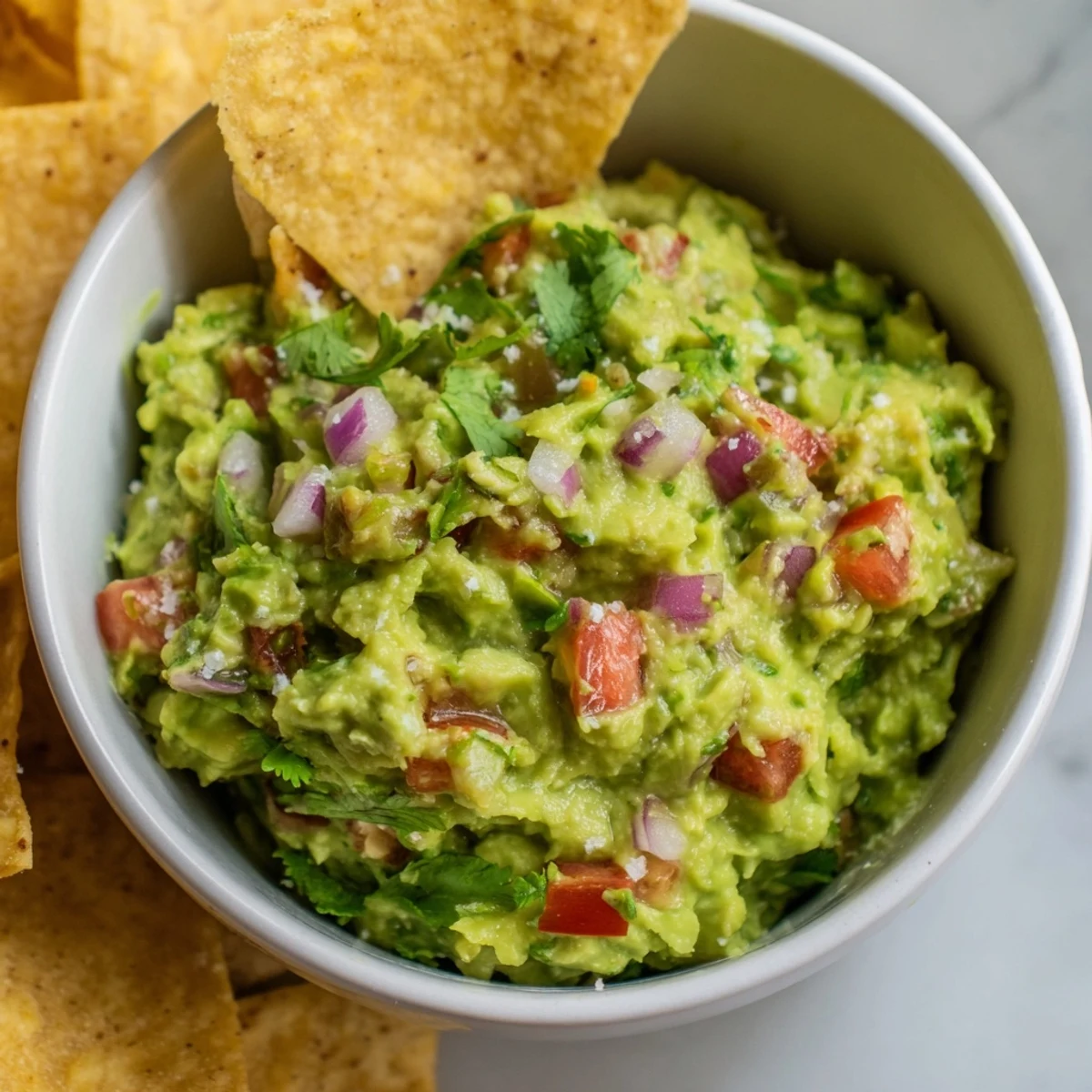 Hausgemachte Maissnacks begleiten würzige Avocado-Speise bei einem gemütlichen Filmabend in den USA.