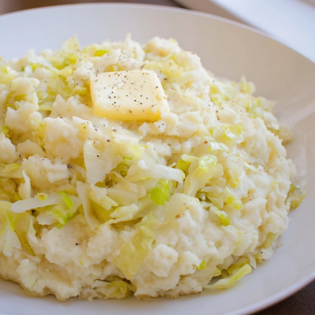 St. Patricks Day Colcannon Mashed Potatoes served hot in a rustic bowl, topped with a melting pat of butter.