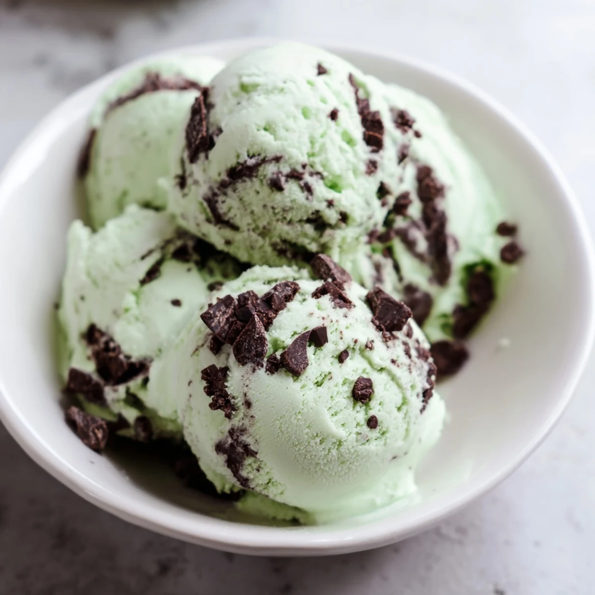 Homemade St. Patricks Day Mint Chocolate Chip Ice Cream with rich chocolate chunks, served in a festive green glass.