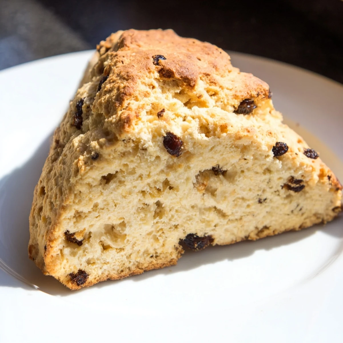 Golden-brown Irish Soda Bread Scones with a crisp crust and soft crumbly interior on a wooden board.