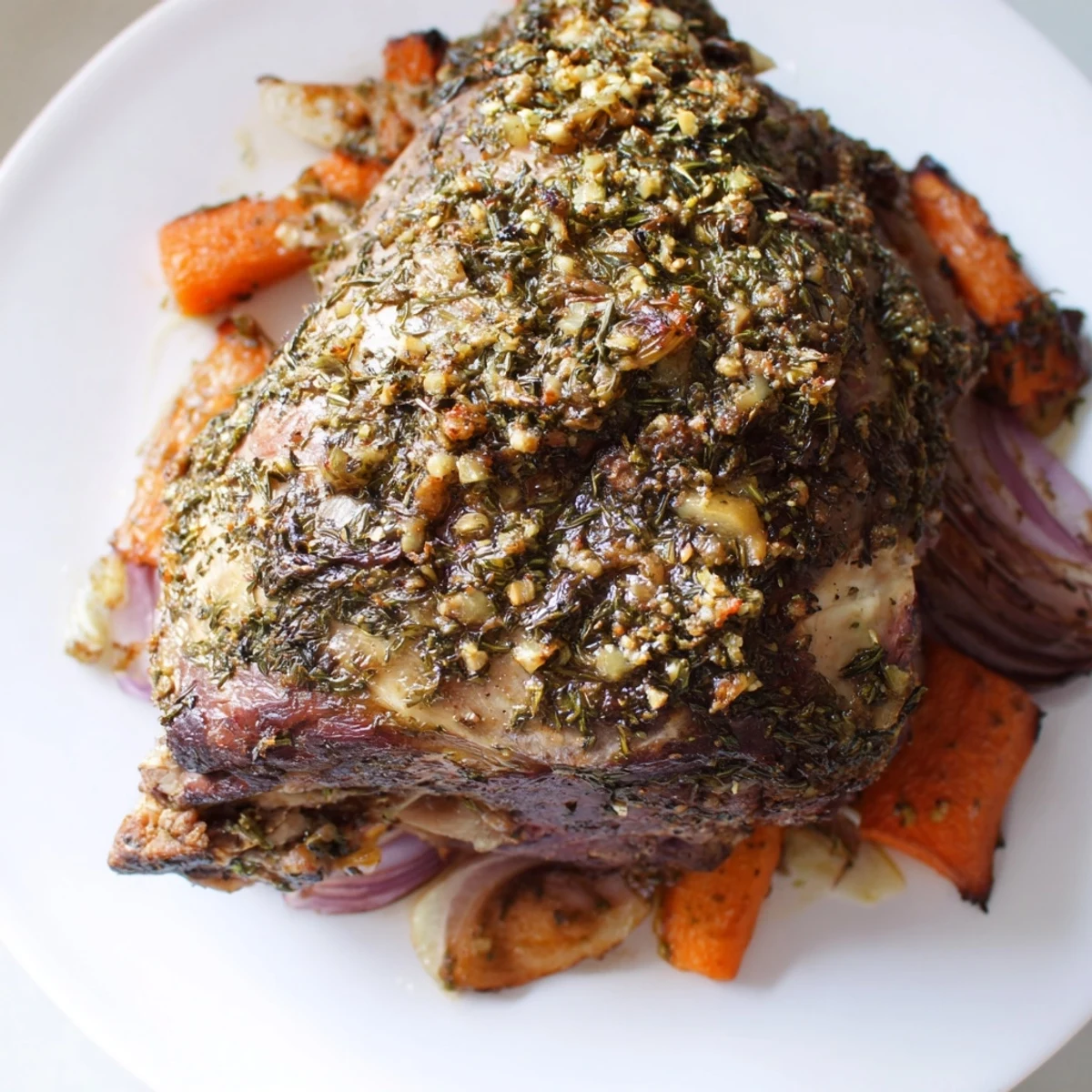 Ein fertig gebackenes Lamm-Schulterstück mit Kräutern, das zartes Fleisch und eine goldene Kruste zeigt, serviert mit geröstetem Gemüse.