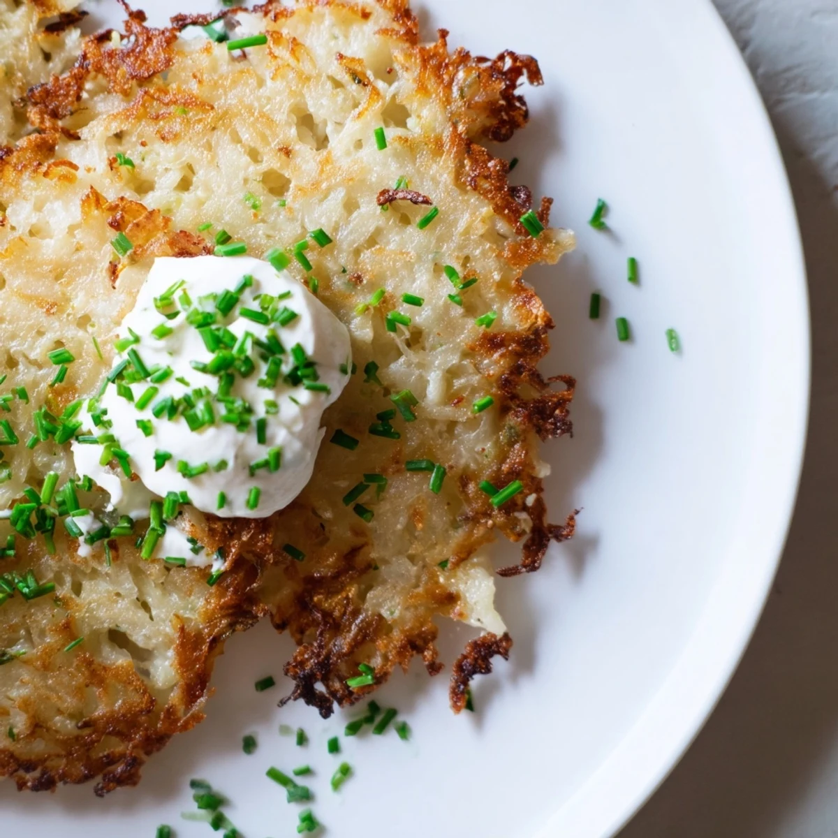 Goldene Irish Boxty mit einem Klecks saurer Sahne auf heißer Platte, knusprig und cremig.
