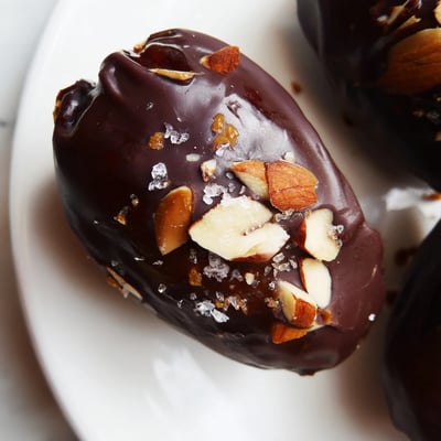 Frisch aus dem Kühlschrank erkalte Schokolade über zähen Dates mit cremiger Mandelbutter und gerösteten Mandeln.
