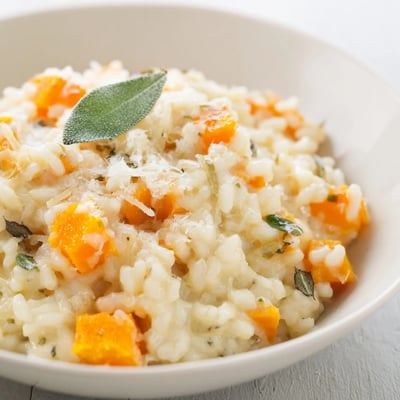 A pan of Winter Squash Risotto with Sage and Parmesan, featuring vibrant orange squash chunks and melted butter, ready for a cozy family dinner.