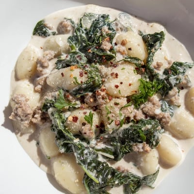 Tender Creamy Gnocchi with Turkey Sausage and Kale garnished with parsley, perfect for a cozy weeknight dinner on a plate.