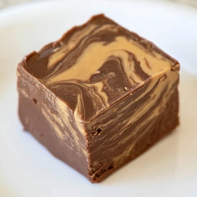 Rich Chocolate Peanut Butter Fudge Squares served on a white plate.