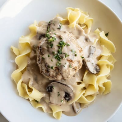 Homemade Turkey Meatball Stroganoff over Egg Noodles garnished with fresh parsley on a rustic plate.