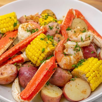 A steaming platter of Cajun Seafood Boil with Corn shows corn, shrimp, crab, sausage, and potatoes