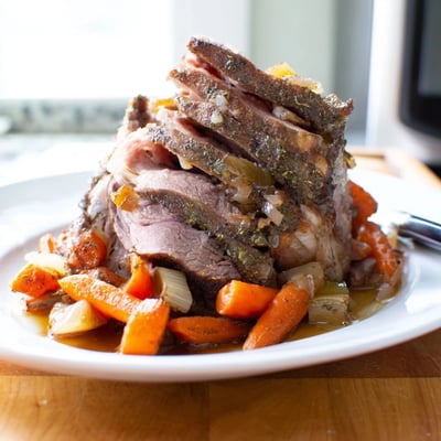 Saftiges, langsam gebratenes Lamm-Schulterstück auf einer Schicht gerösteter Karotten und Zwiebeln.